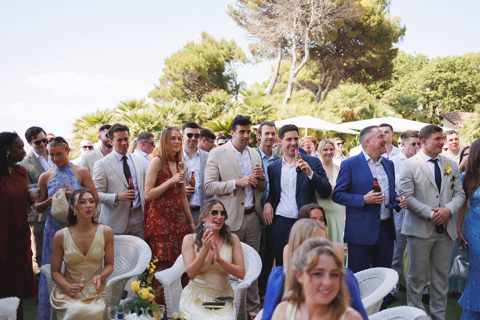 Invitati riuniti all’aperto fra gli alberi durante l’aperitivo a Palazzo Belmonte.