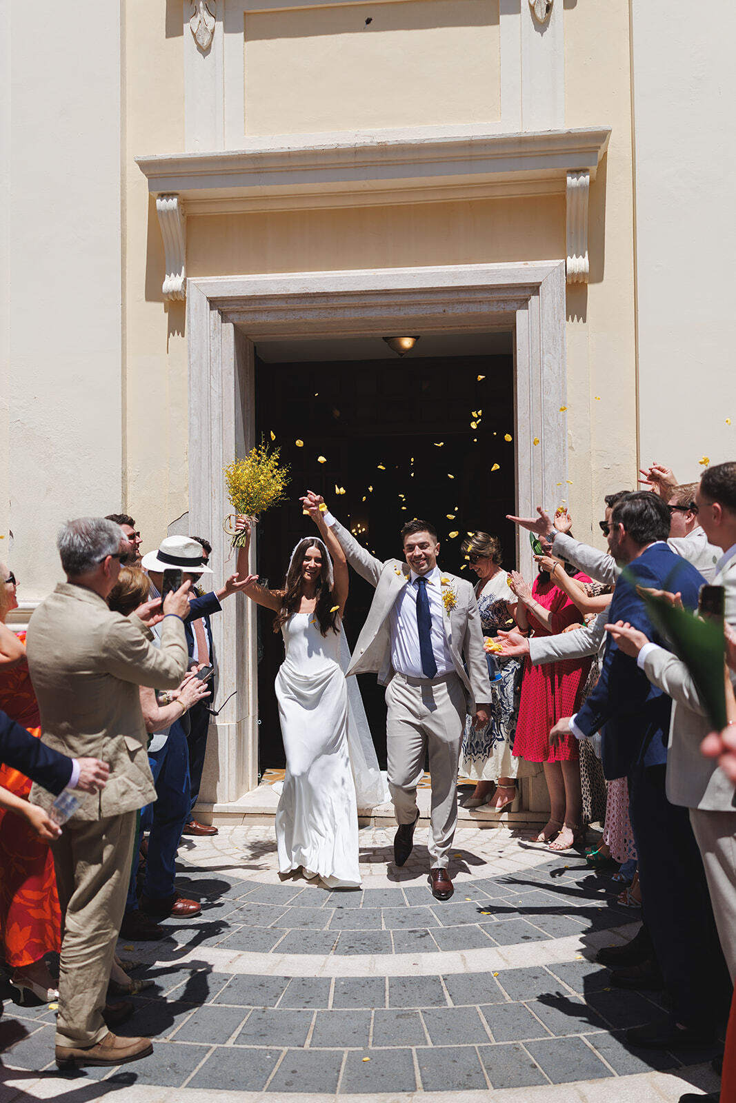 Kathy e Alex escono dalla chiesa con le braccia alzate fra gli invitati e i petali.
