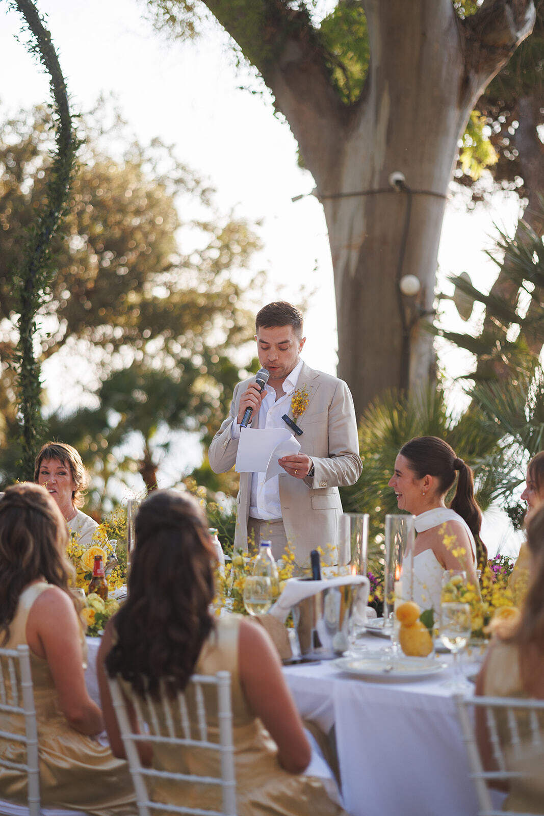 Alex parla al microfono accanto alla tavola del matrimonio all’aperto a Palazzo Belmonte.