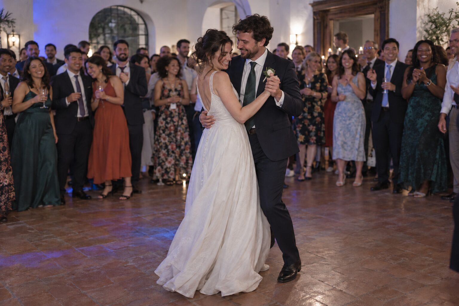 Bride and groom enjoying their first dance, surrounded by wedding guests inside a reception room.