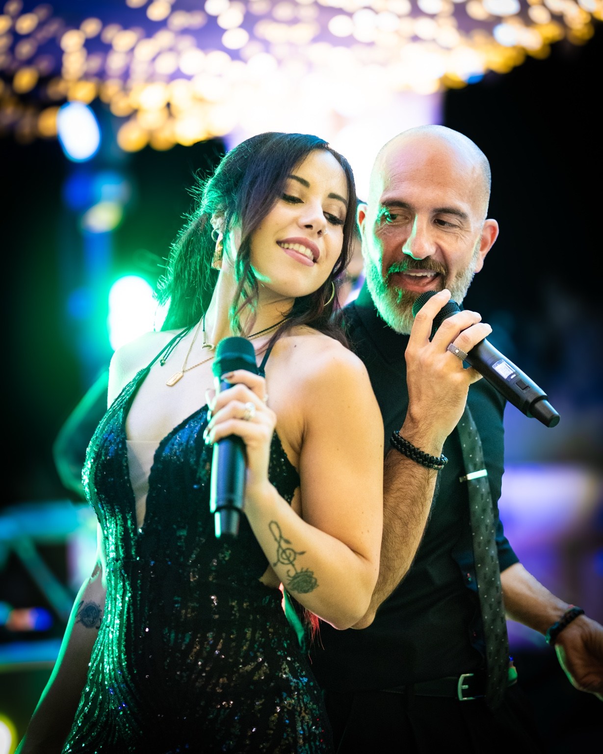 Male and female singers performing together with handheld microphones.