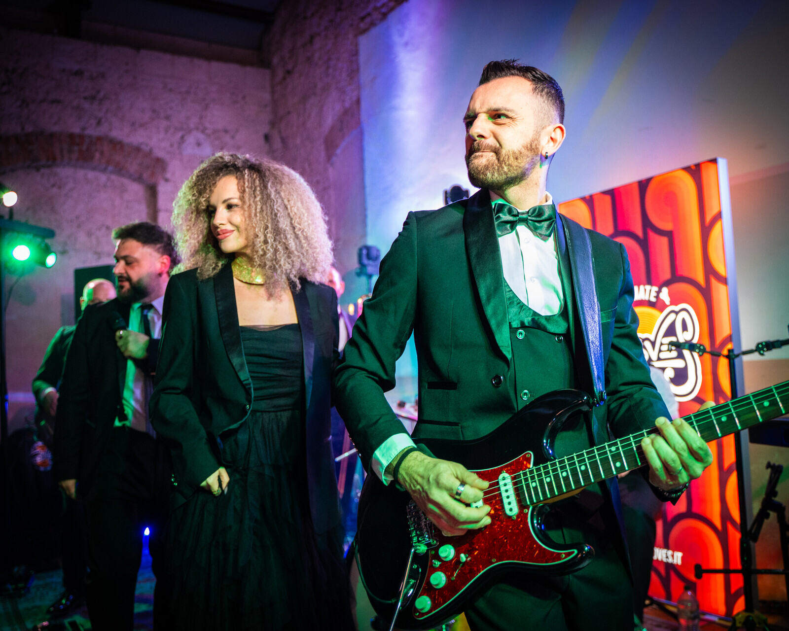 Cantanti e chitarrista dei The Gloves si esibiscono sul palco illuminato durante il matrimonio.