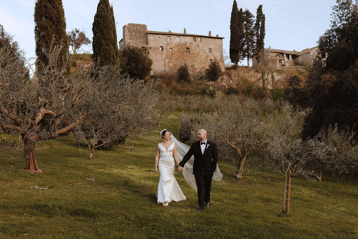 Rebecca e Hugh camminano mano nella mano tra gli ulivi sotto gli edifici di Borgo di Tragliata.